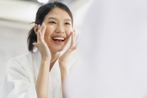 attractive freshness asian woman clean face fresh water with care look to mirror in bathroom home background - hnhskincare.co.id